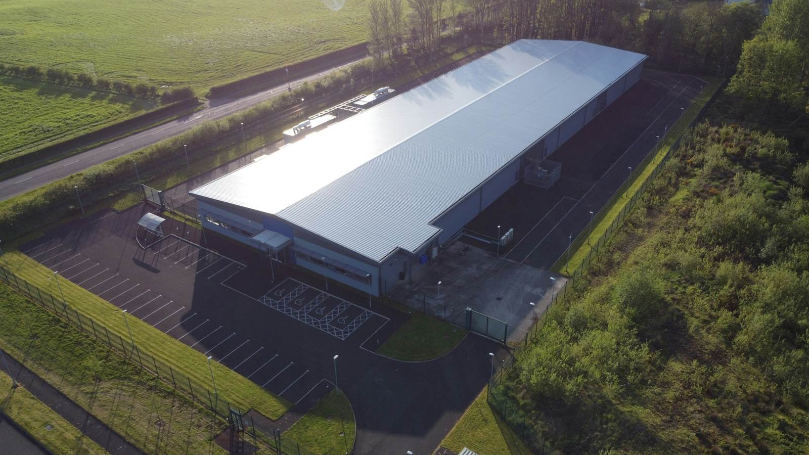 Aerial view of a large industrial building beside woodland