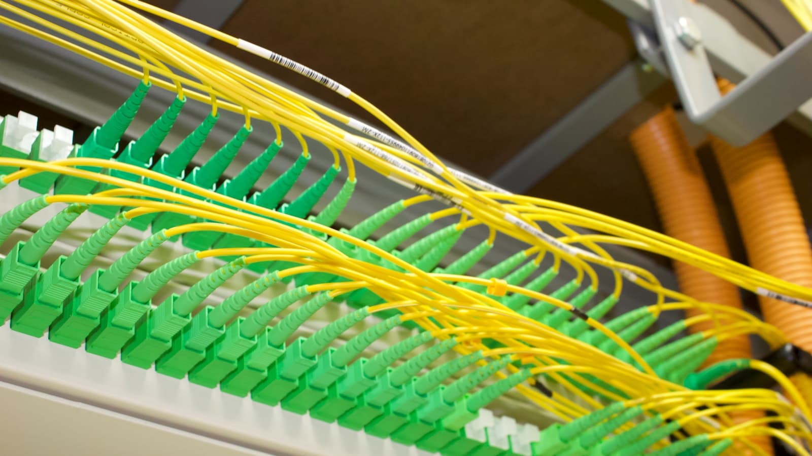 Yellow fiber-optic cables connected to green ports