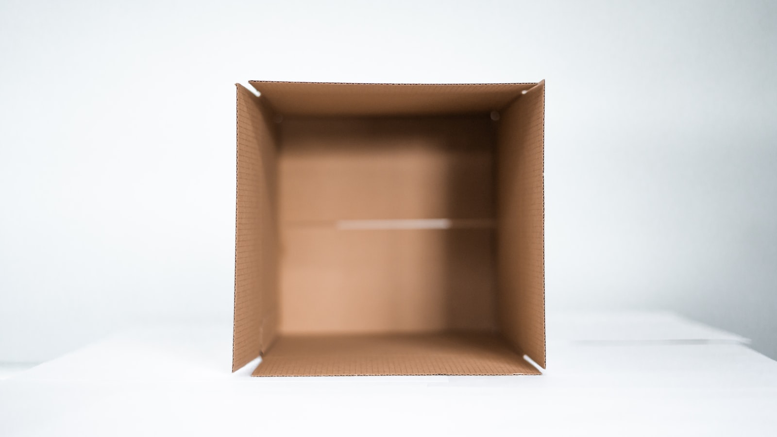 Empty open cardboard box on a white surface
