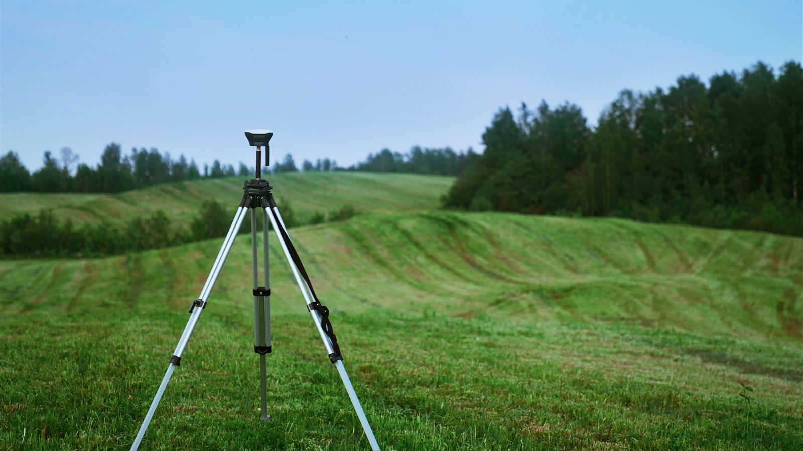 Surveying receiver on a tripod in a grassy field