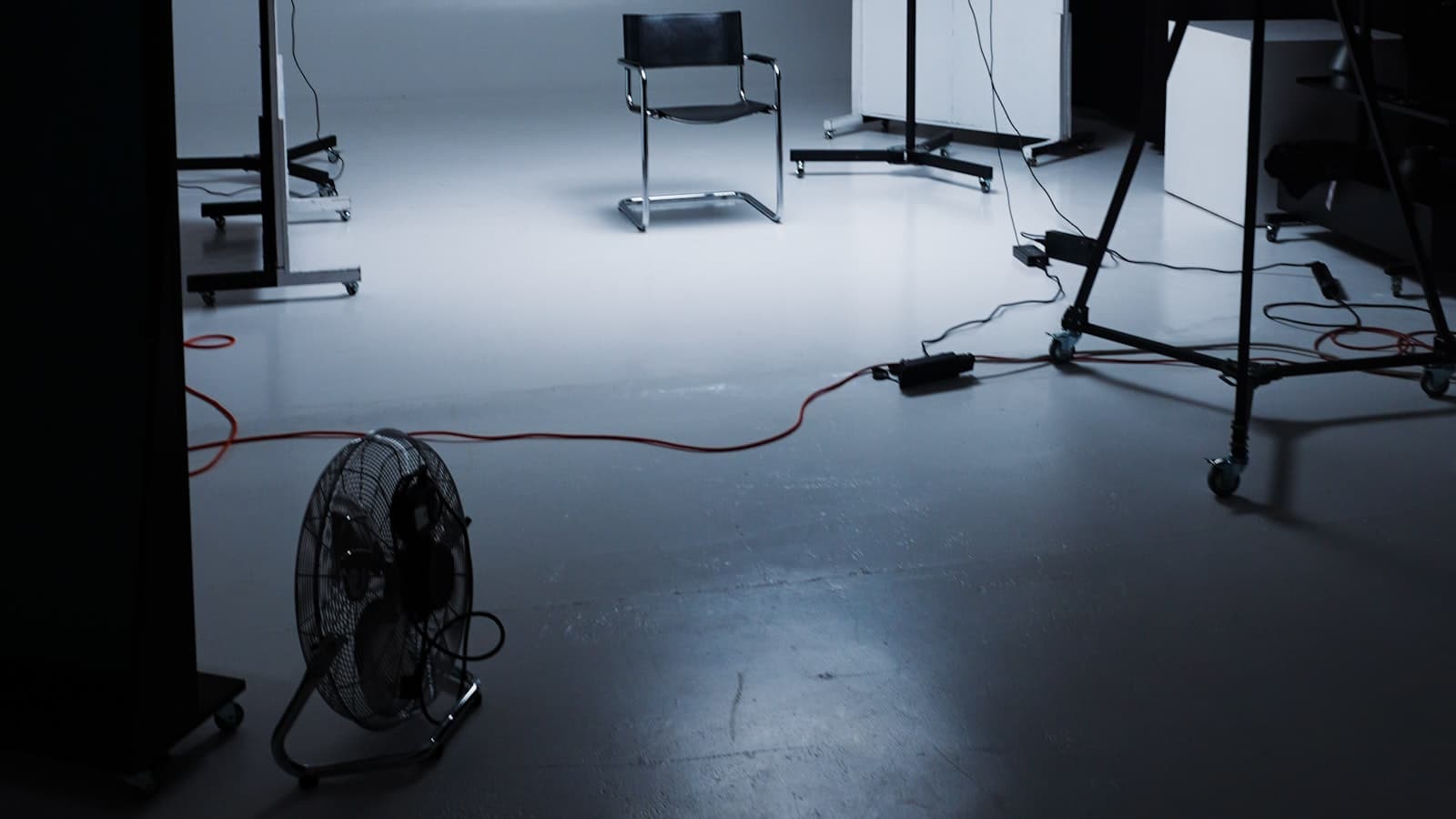 Empty photo studio with lighting stands, a chair, and a floor fan